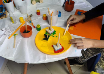 Mesa com pincéis e tintas para desenvolvimento das crianças